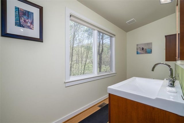 laundry area featuring a sink, baseboards, visible vents, and wood finished floors