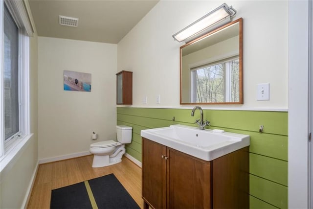 bathroom featuring toilet, wood finished floors, visible vents, baseboards, and vanity