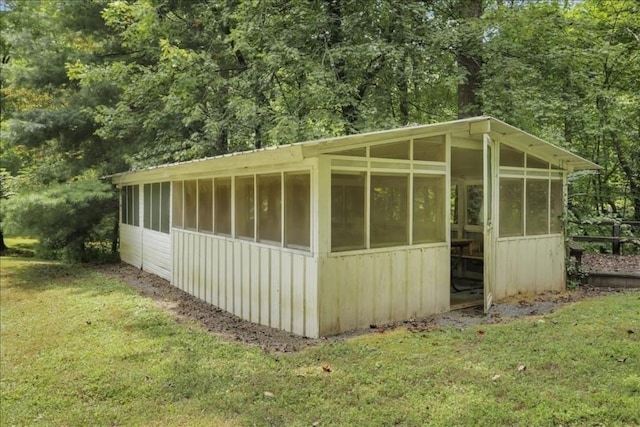 view of outdoor structure featuring a sunroom and a yard