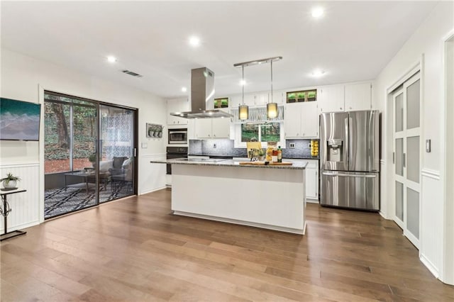 kitchen with appliances with stainless steel finishes, hanging light fixtures, a center island, island range hood, and white cabinets