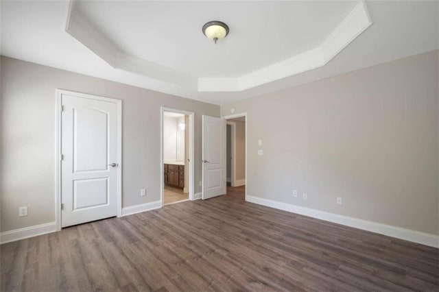 5737 Russell Ct, Douglasville, GA 30135 - unfurnished bedroom featuring baseboards, a raised ceiling, connected bathroom, and wood finished floors