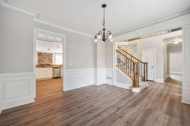 5737 Russell Ct, Douglasville, GA 30135 - unfurnished dining area featuring an inviting chandelier, ornamental molding, a wainscoted wall, wood finished floors, and stairs