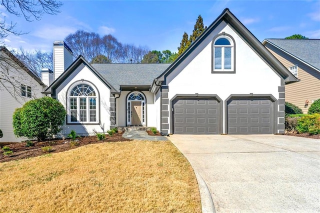 view of front of home with a chimney, stucco siding, concrete driveway, and a front lawn