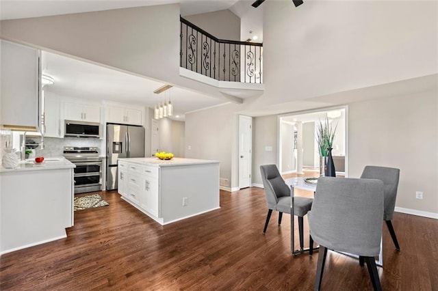 kitchen featuring dark wood finished floors, a kitchen island, white cabinets, and stainless steel appliances