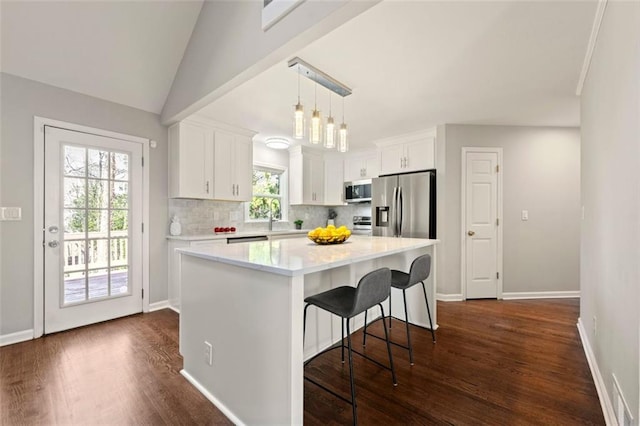 kitchen featuring dark wood finished floors, light countertops, decorative backsplash, appliances with stainless steel finishes, and white cabinets