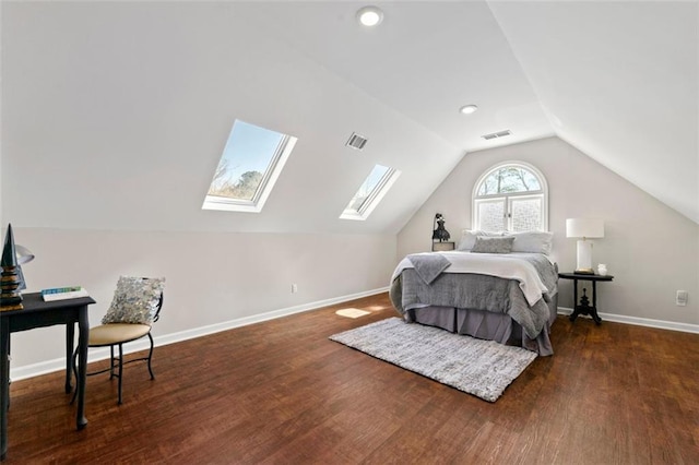 bedroom with visible vents, vaulted ceiling with skylight, baseboards, and wood finished floors