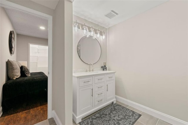 bathroom featuring a spacious closet, visible vents, baseboards, tile patterned floors, and vanity