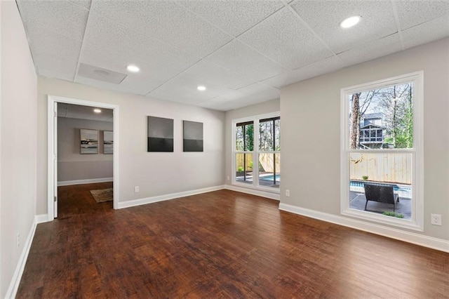 unfurnished room featuring recessed lighting, dark wood-style floors, baseboards, and a drop ceiling