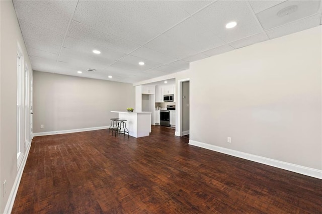 unfurnished living room featuring recessed lighting, dark wood-style floors, and baseboards