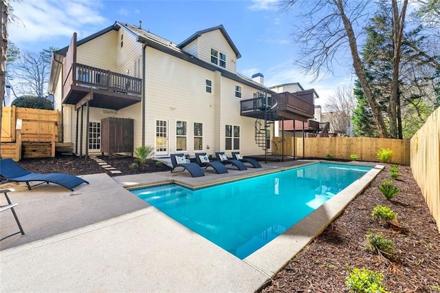 view of pool with a patio, a fenced backyard, a wooden deck, a fenced in pool, and stairs