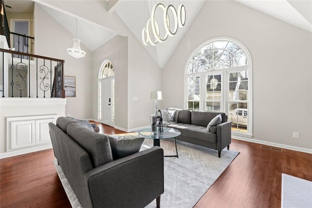 living area with high vaulted ceiling, an inviting chandelier, and wood finished floors