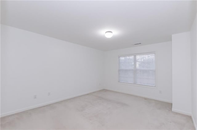 empty room featuring baseboards, visible vents, and light colored carpet