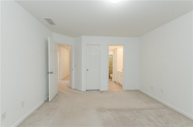 unfurnished bedroom featuring light colored carpet, visible vents, baseboards, and ensuite bathroom