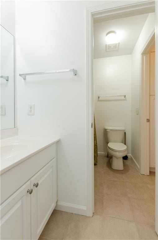 bathroom featuring baseboards, vanity, toilet, and tile patterned floors