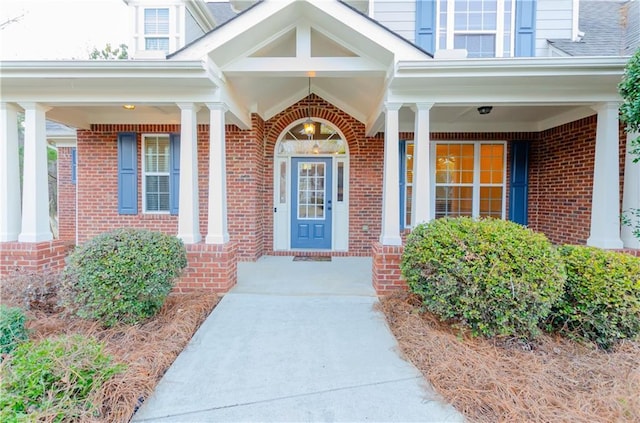 entrance to property with covered porch and brick siding