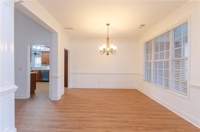 unfurnished dining area with ceiling fan with notable chandelier, light wood-style floors, baseboards, and crown molding