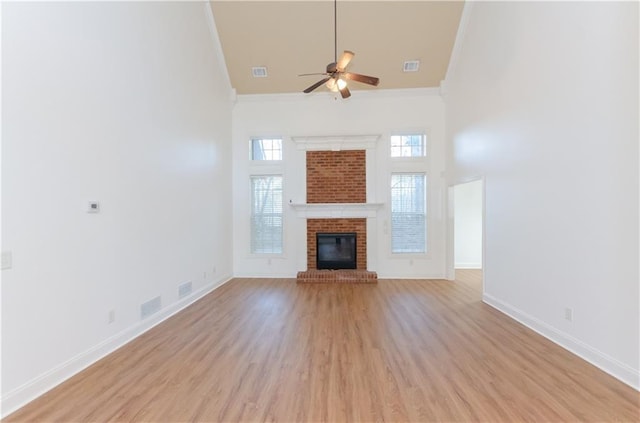 unfurnished living room with baseboards, a high ceiling, light wood-style floors, and crown molding