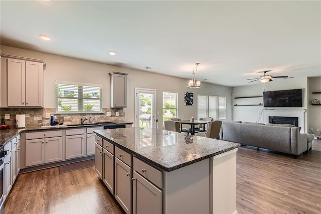 2486 Bear Mountain St, Lithonia, GA 30058 - kitchen with gray cabinetry, a center island, backsplash, wood finished floors, and a fireplace