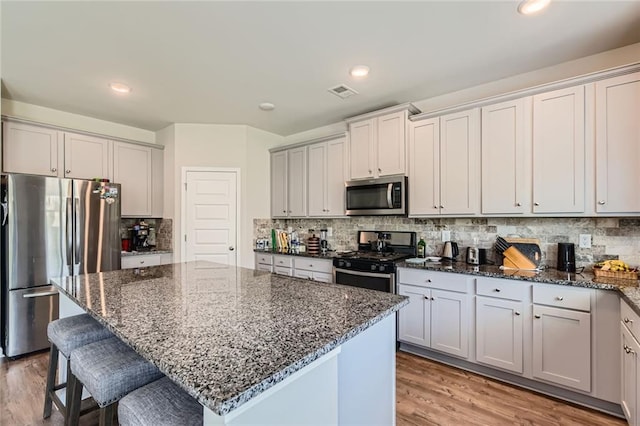 2486 Bear Mountain St, Lithonia, GA 30058 - kitchen featuring stainless steel appliances, dark stone counters, a breakfast bar area, backsplash, and recessed lighting