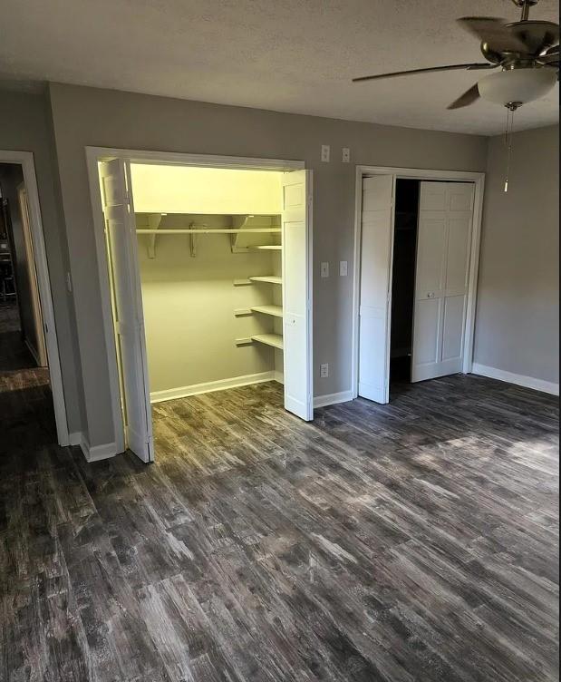 unfurnished bedroom featuring a textured ceiling, dark hardwood / wood-style floors, and ceiling fan