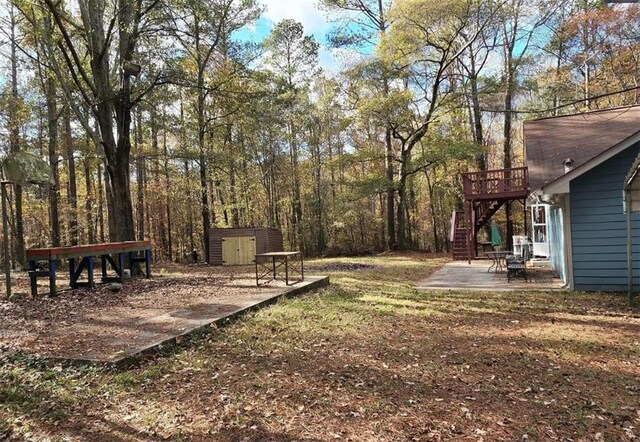 view of yard featuring a storage shed, a deck, and a patio