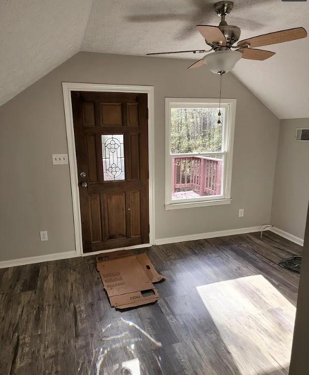 foyer entrance with vaulted ceiling, ceiling fan, a textured ceiling, and dark hardwood / wood-style floors