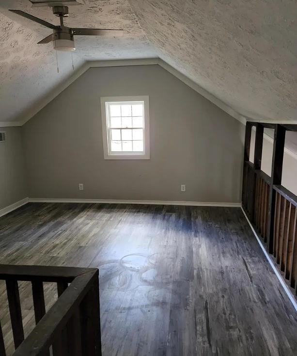 bonus room featuring a textured ceiling, dark hardwood / wood-style flooring, vaulted ceiling, and ceiling fan