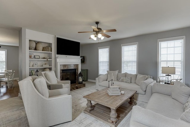 living room featuring light wood-type flooring, ceiling fan, and a high end fireplace