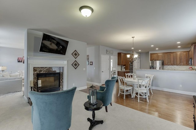 living room featuring an inviting chandelier, light hardwood / wood-style floors, and a fireplace