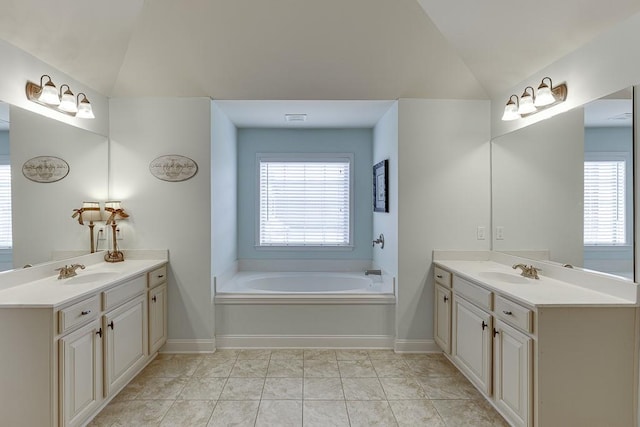 bathroom with tile patterned flooring, vanity, a tub to relax in, and vaulted ceiling