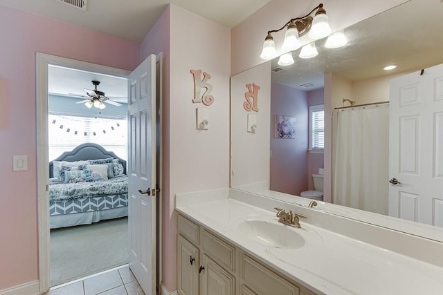 bathroom featuring tile patterned floors, walk in shower, vanity, toilet, and ceiling fan