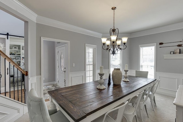 carpeted dining room featuring a barn door, a healthy amount of sunlight, and crown molding