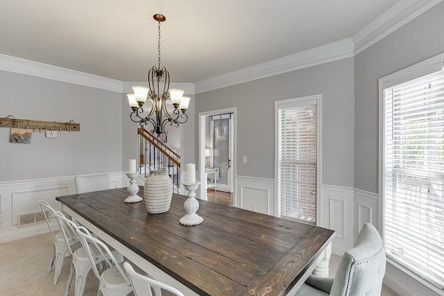 carpeted dining room featuring an inviting chandelier and ornamental molding