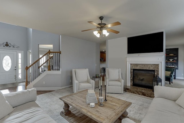 living room with a premium fireplace, ceiling fan, and light hardwood / wood-style flooring