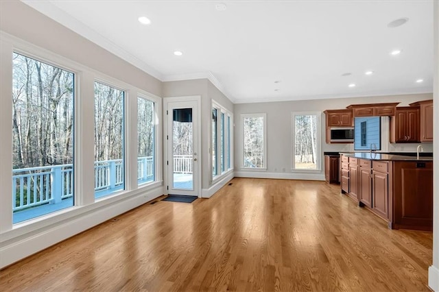 kitchen with recessed lighting, stainless steel microwave, light wood-style floors, crown molding, and baseboards