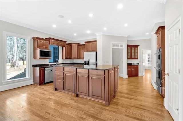 kitchen featuring stainless steel appliances, dark countertops, ornamental molding, light wood-type flooring, and a center island
