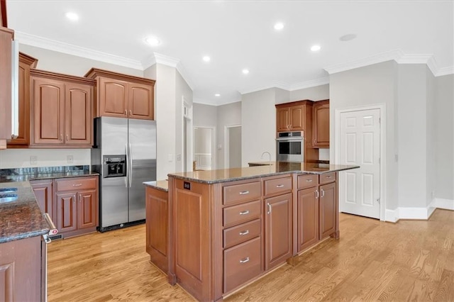 kitchen with dark stone countertops, a kitchen island with sink, stainless steel appliances, light wood finished floors, and recessed lighting