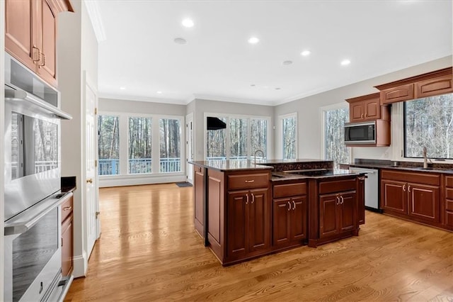 kitchen with crown molding, a sink, built in microwave, light wood-style floors, and dishwasher