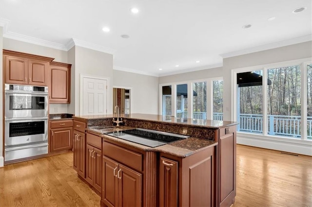 kitchen featuring black electric cooktop, stainless steel double oven, a sink, a warming drawer, and light wood-type flooring
