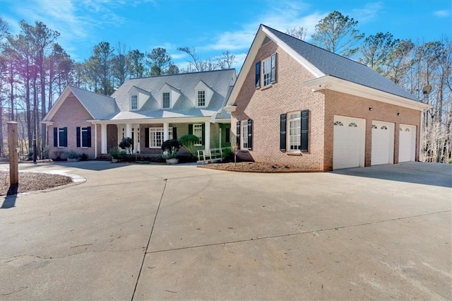 new england style home with brick siding, a porch, and concrete driveway