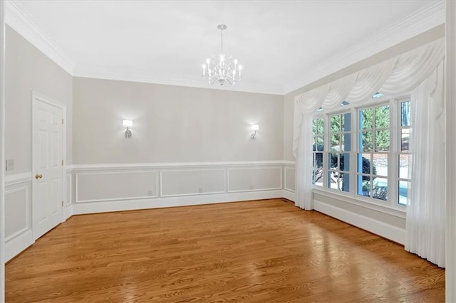 unfurnished dining area with wainscoting, crown molding, wood finished floors, and a chandelier