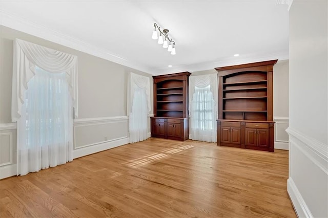 interior space featuring light wood-type flooring, a decorative wall, and crown molding