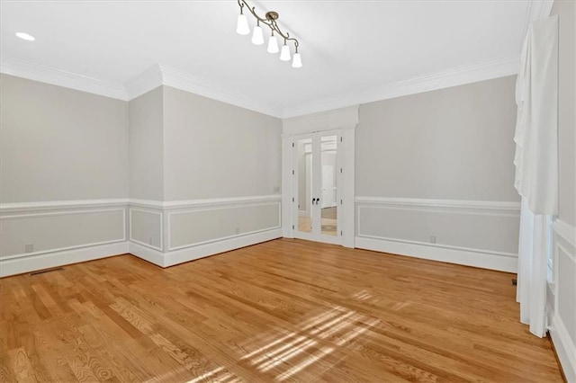 unfurnished dining area with crown molding, wood finished floors, and a wainscoted wall