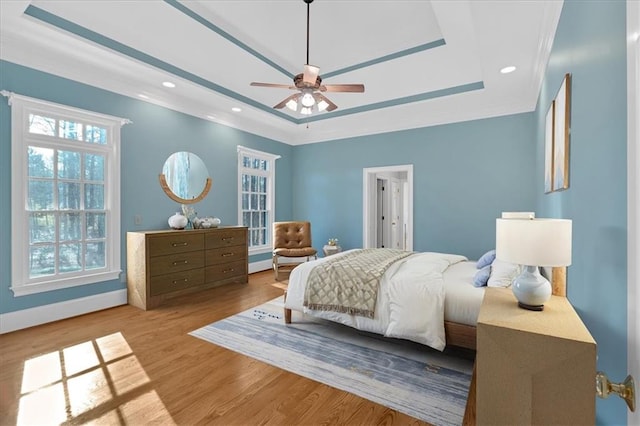 bedroom featuring baseboards, a tray ceiling, wood finished floors, and recessed lighting