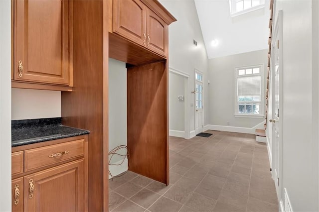 mudroom with baseboards, visible vents, and high vaulted ceiling