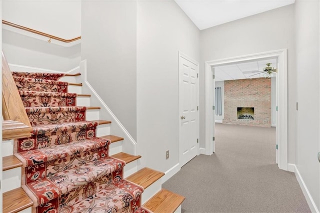 stairs featuring a fireplace, baseboards, and carpet