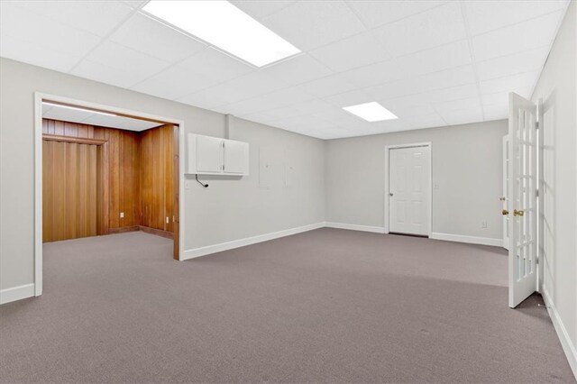 basement with dark carpet, baseboards, and a drop ceiling