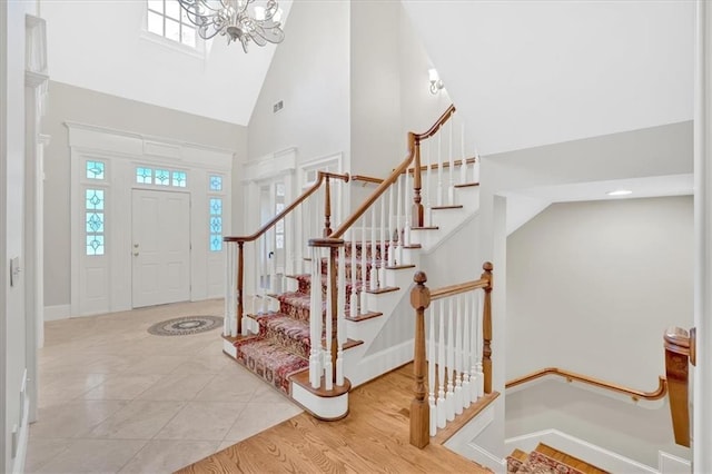 foyer entrance with an inviting chandelier, baseboards, high vaulted ceiling, and stairway