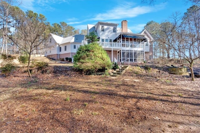 back of property featuring a chimney, a sunroom, and stairs