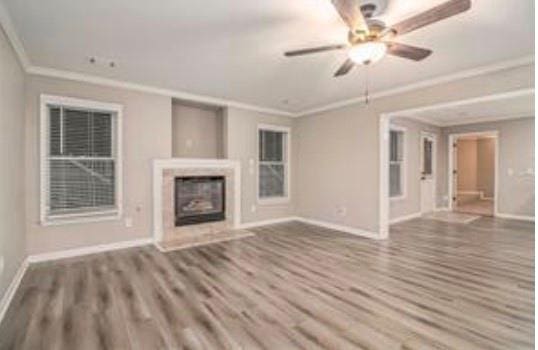 4519 Mossey Dr, Lithonia, GA 30038 - unfurnished living room featuring crown molding, baseboards, wood finished floors, a glass covered fireplace, and ceiling fan